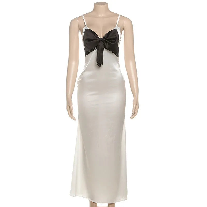 Mannequin wearing a white evening gown with a black bow on a white background