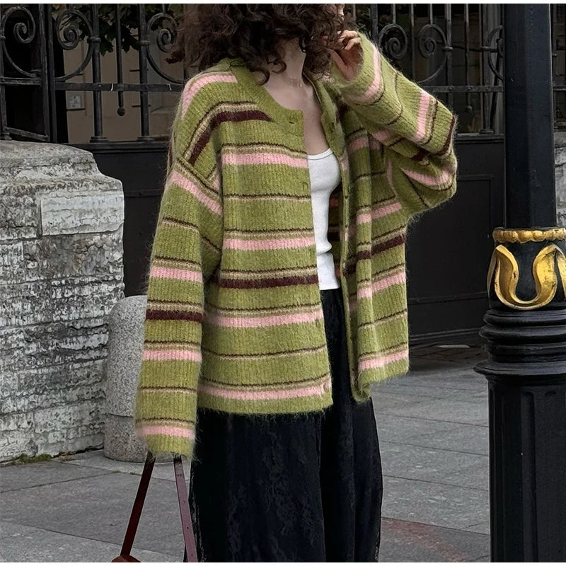 Person wearing a green and pink striped cardigan in an urban setting