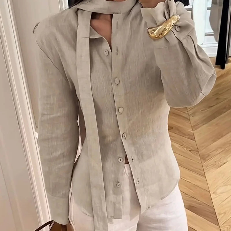 Person wearing a beige shirt with a gold brooch in an indoor setting