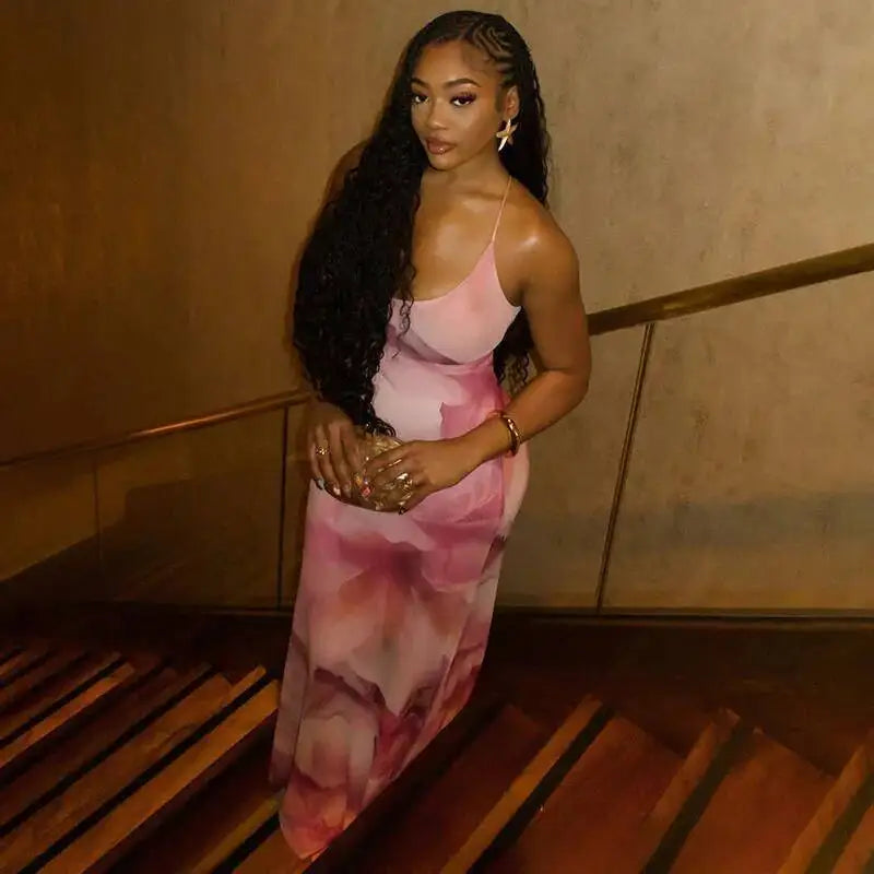 Woman in a pink floral dress standing indoors with a neutral background