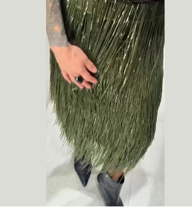 Person wearing a green tinsel skirt with a plain background