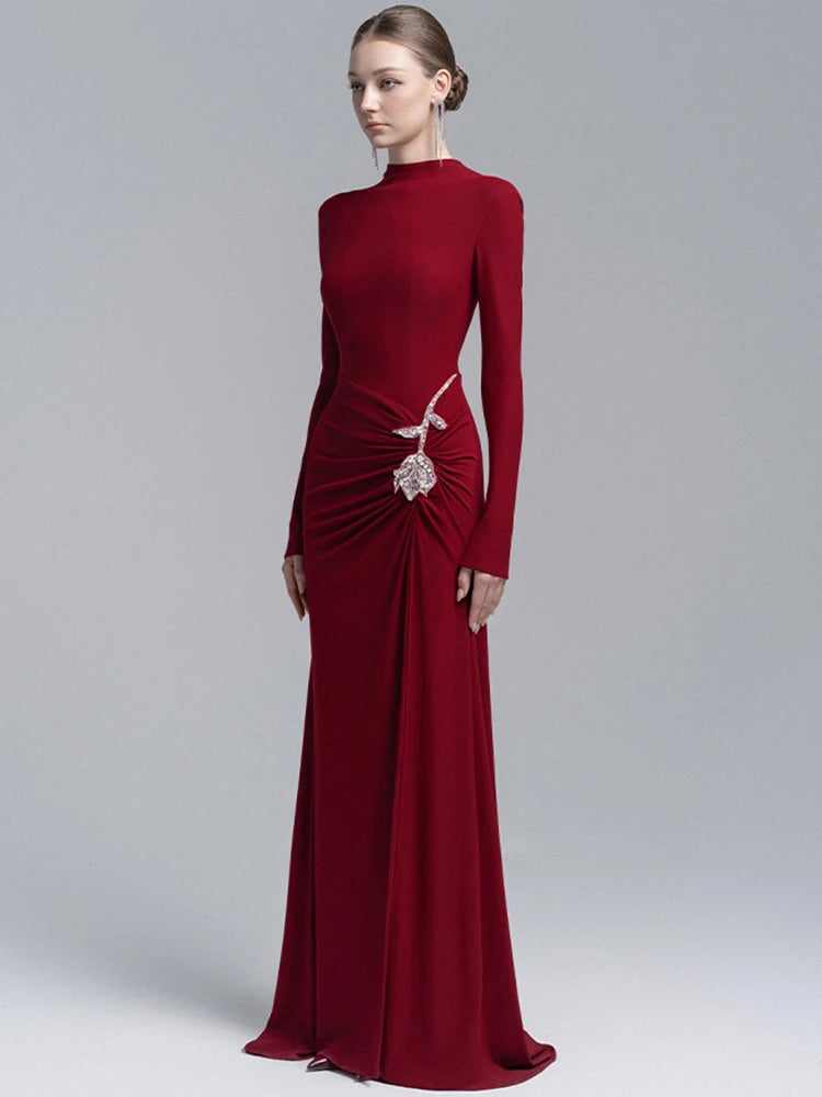 Red evening gown with long sleeves and a decorative element on a gray background