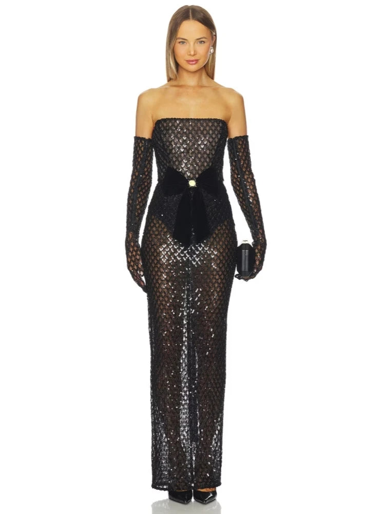 Woman wearing a black sequin gown with long sleeves on a white background