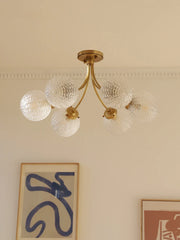 A modern glass ball ceiling light fixture hanging in a stylish living room. Golden Atelier 2