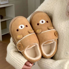 Person holding brown cartoon bear house slippers.