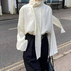 Woman in a flowing polka dot blouse with bell sleeves and a scarf tie