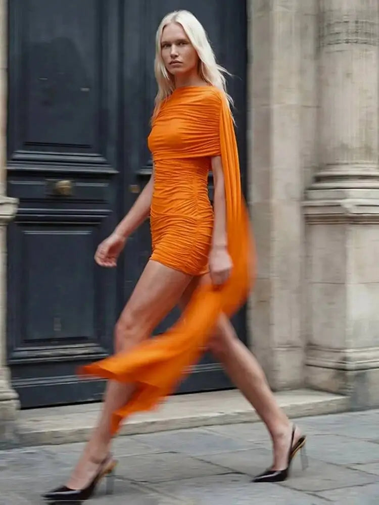 Woman in an orange dress walking on a street with a blurred background