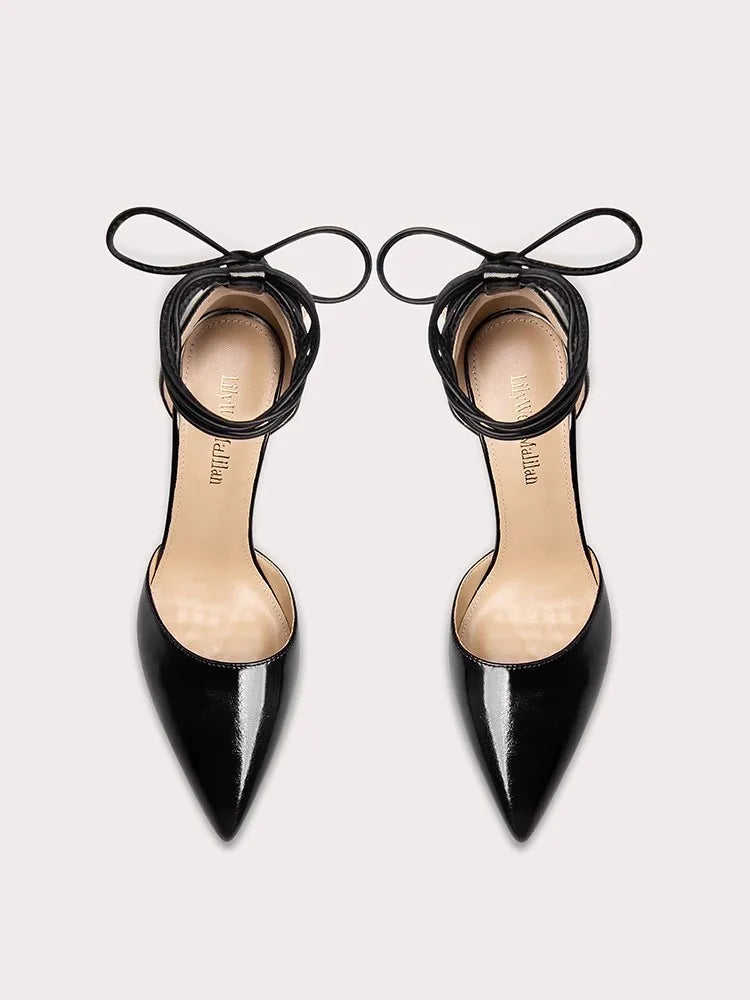 Black pointed-toe high heels with thin straps on a light gray background