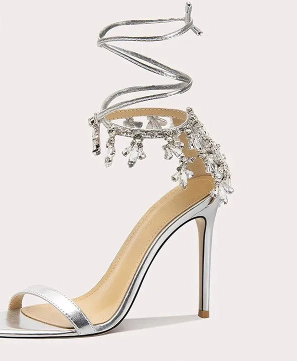 Silver high-heeled shoe with embellishments on a white background