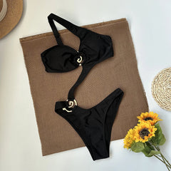 Black one piece swimsuit with asymmetrical strap and gold hardware laid flat