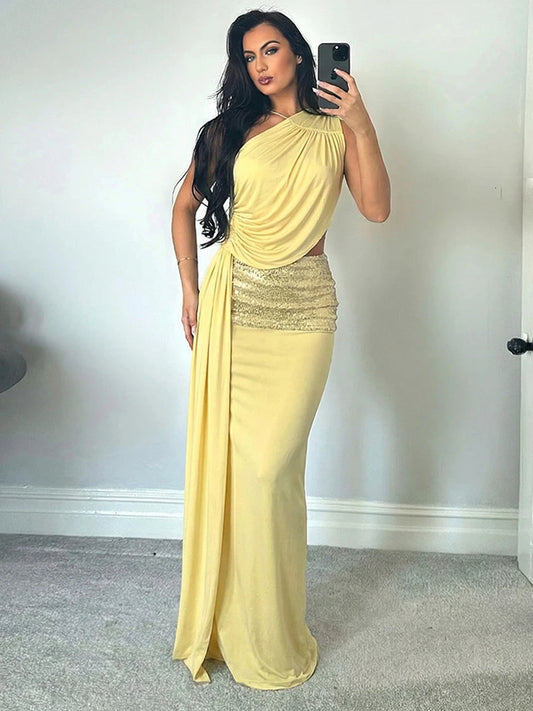 Woman taking a mirror selfie wearing a yellow evening gown with a white wall background