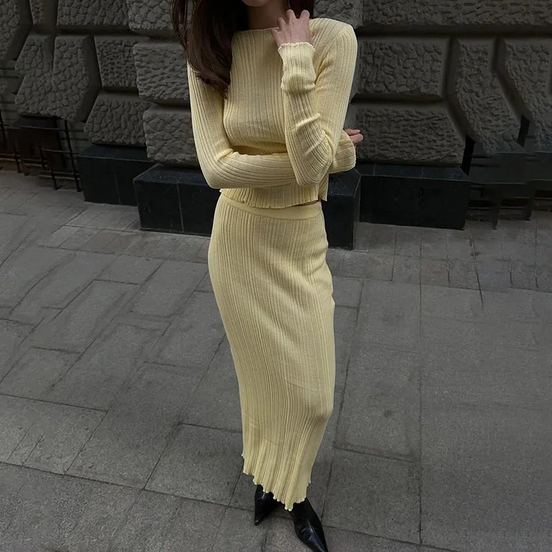 Person wearing a yellow ribbed knit outfit standing on a stone pavement.
