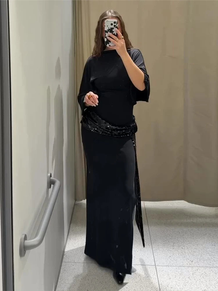 Person wearing a black outfit with a long skirt in a bathroom setting.