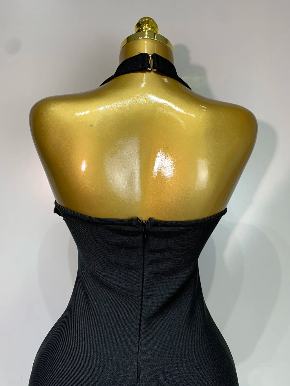 Black dress on a gold mannequin against a white background