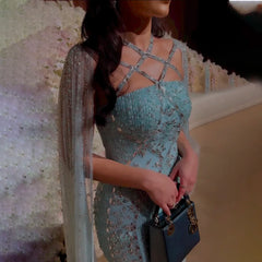  A model wearing the aqua mermaid evening gown with cape sleeves, showcasing its flattering silhouette and graceful train. Golden Atelier 3