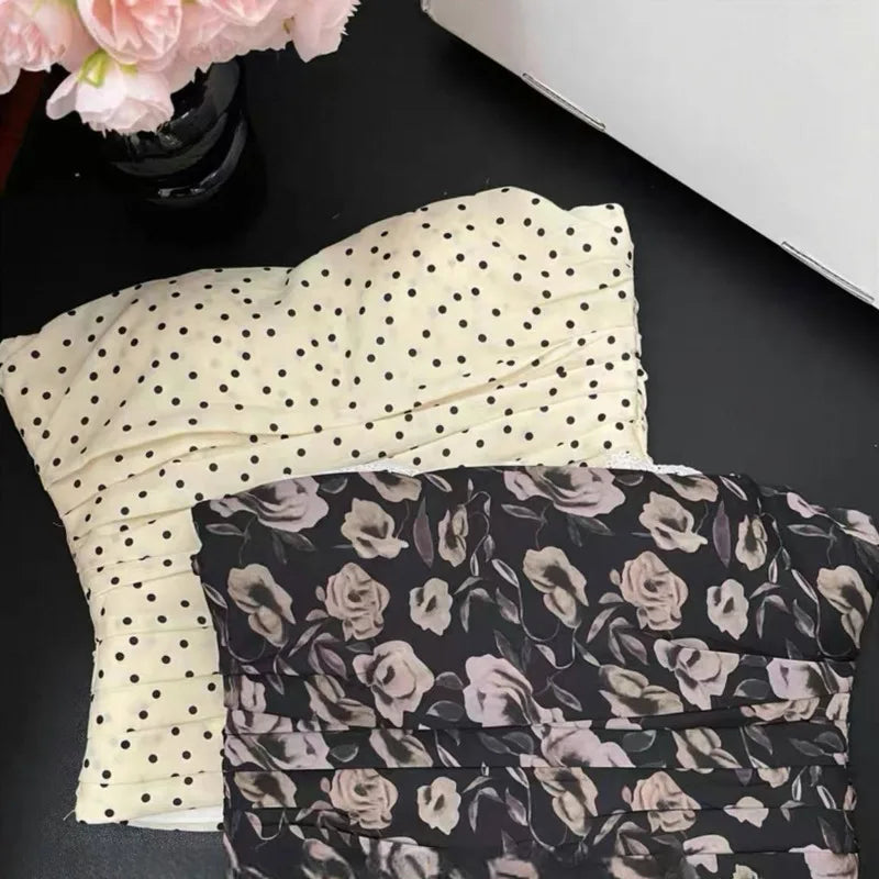 Two folded pieces of fabric, one with black polka dots and the other with floral pattern, on a dark surface.