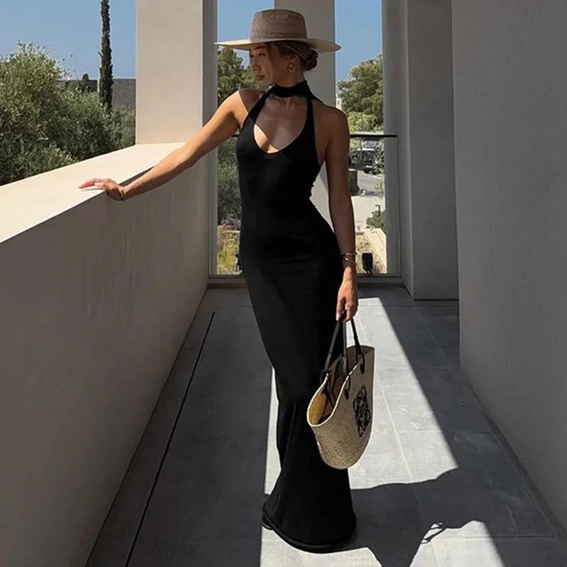 Woman in a black dress and straw hat standing on a modern patio