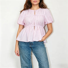 Model wearing a pink striped puff sleeve button-front peplum top with blue jeans