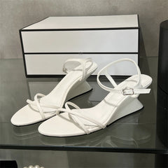 Pair of White hollow-out wedge sandals with an ankle strap, showcasing their stylish design. Golden Atelier 2