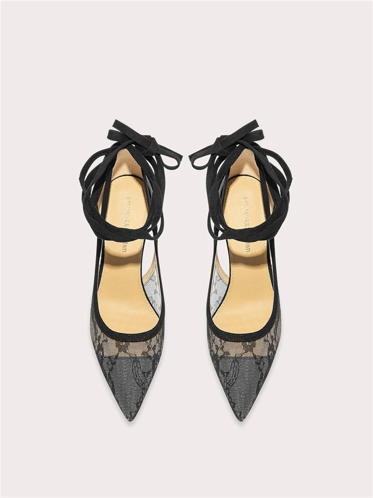 Pair of black lace-up high-heeled shoes on a light gray background