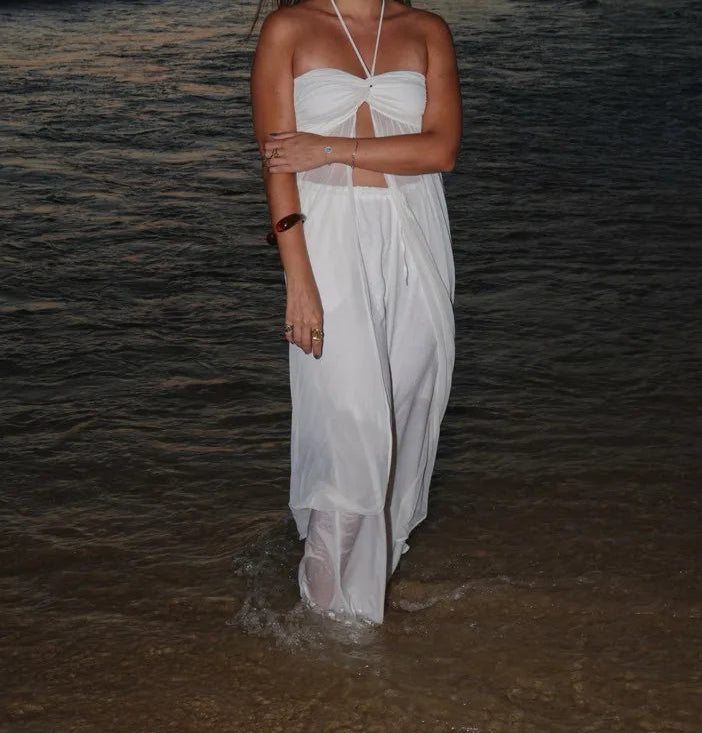 Woman in a white dress standing in shallow water at night.