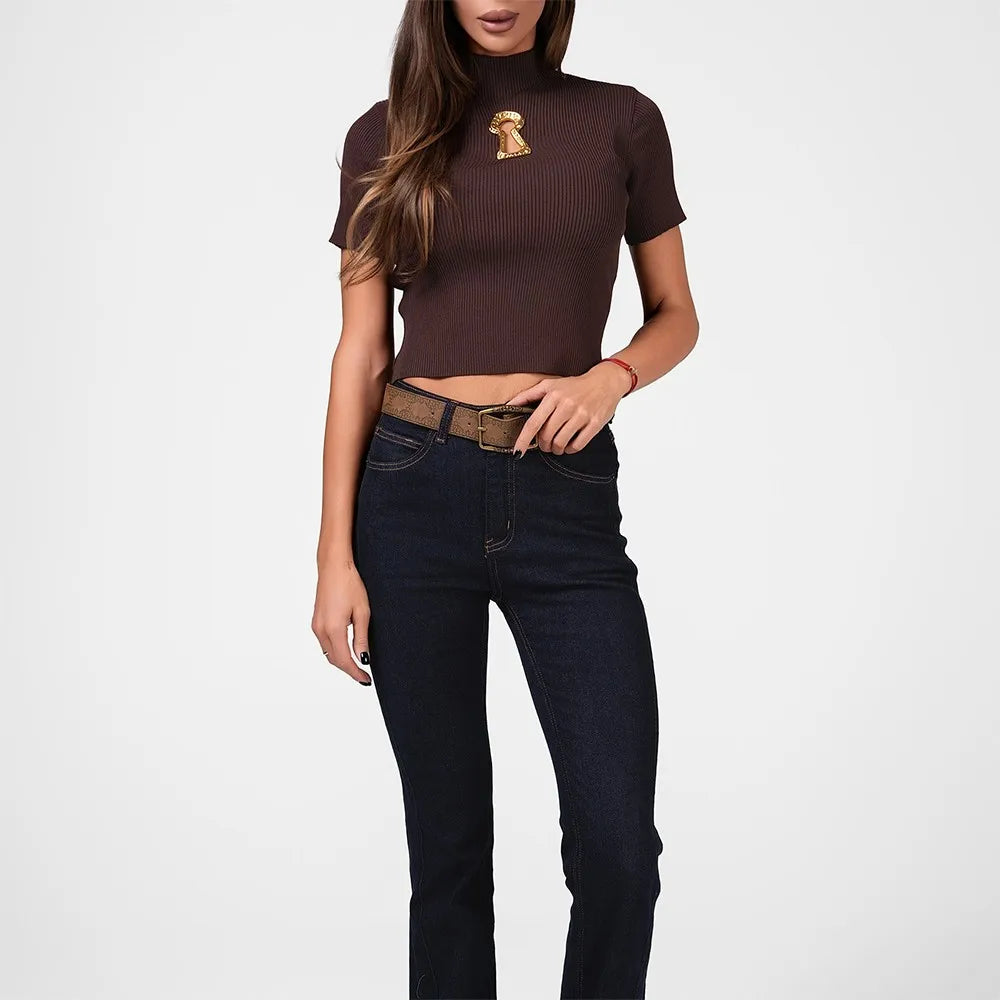 Woman wearing a brown ribbed turtleneck and dark jeans on a white background