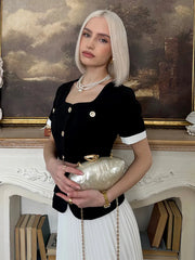 Woman holding a clutch in front of a painting