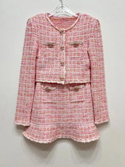 Pink tweed suit with gold buttons on a white hanger against a light gray background