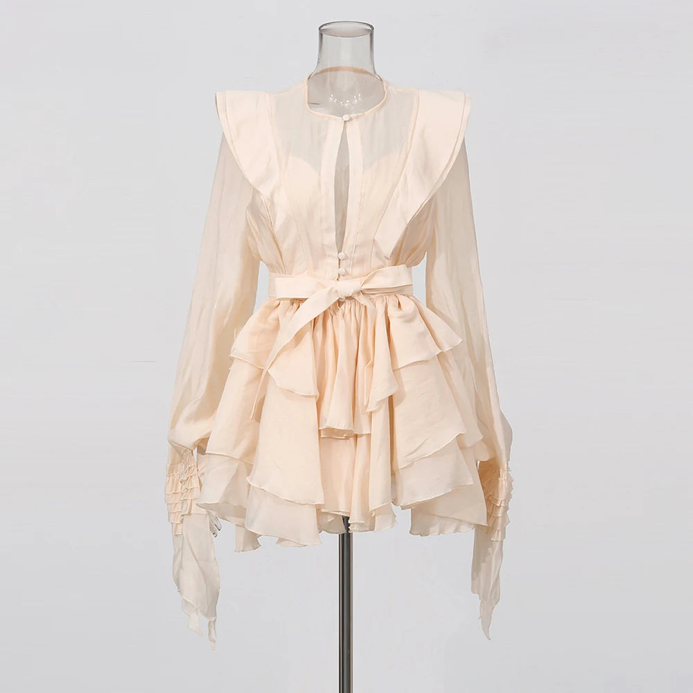 Beige ruffled blouse on a mannequin against a plain background