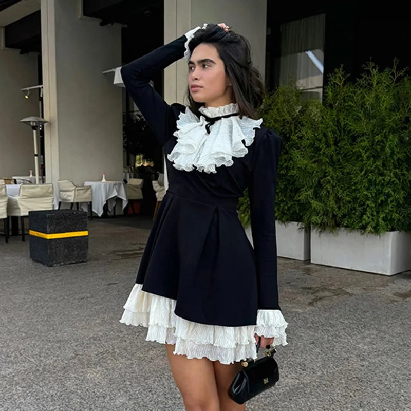 Woman wearing a black and white dress with ruffled details outdoors.