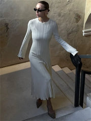 Woman in a white dress standing on a stone staircase with a textured wall background