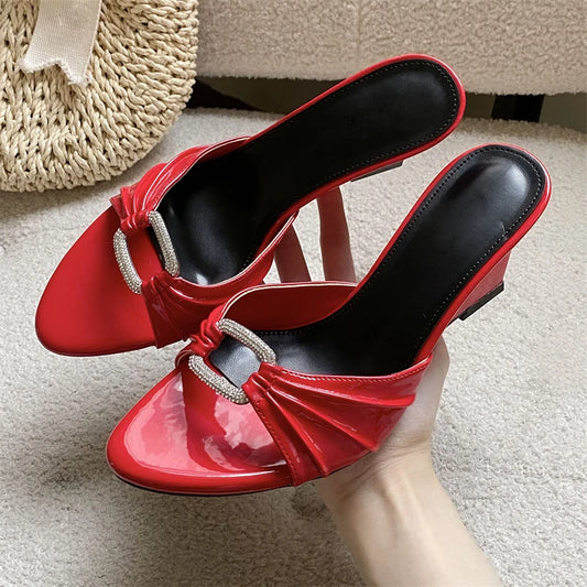 Red patent leather wedge slippers with crystal buckle and pleated detail.