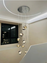 Modern ceiling light fixture with hanging glass spheres in a room with a television.