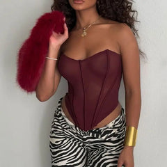 Woman wearing a burgundy strapless top and zebra print pants, holding a red fur clutch.