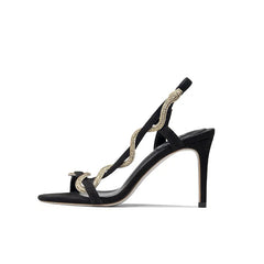Profile view of black stiletto sandals showcasing the high heel and rhinestone detail.