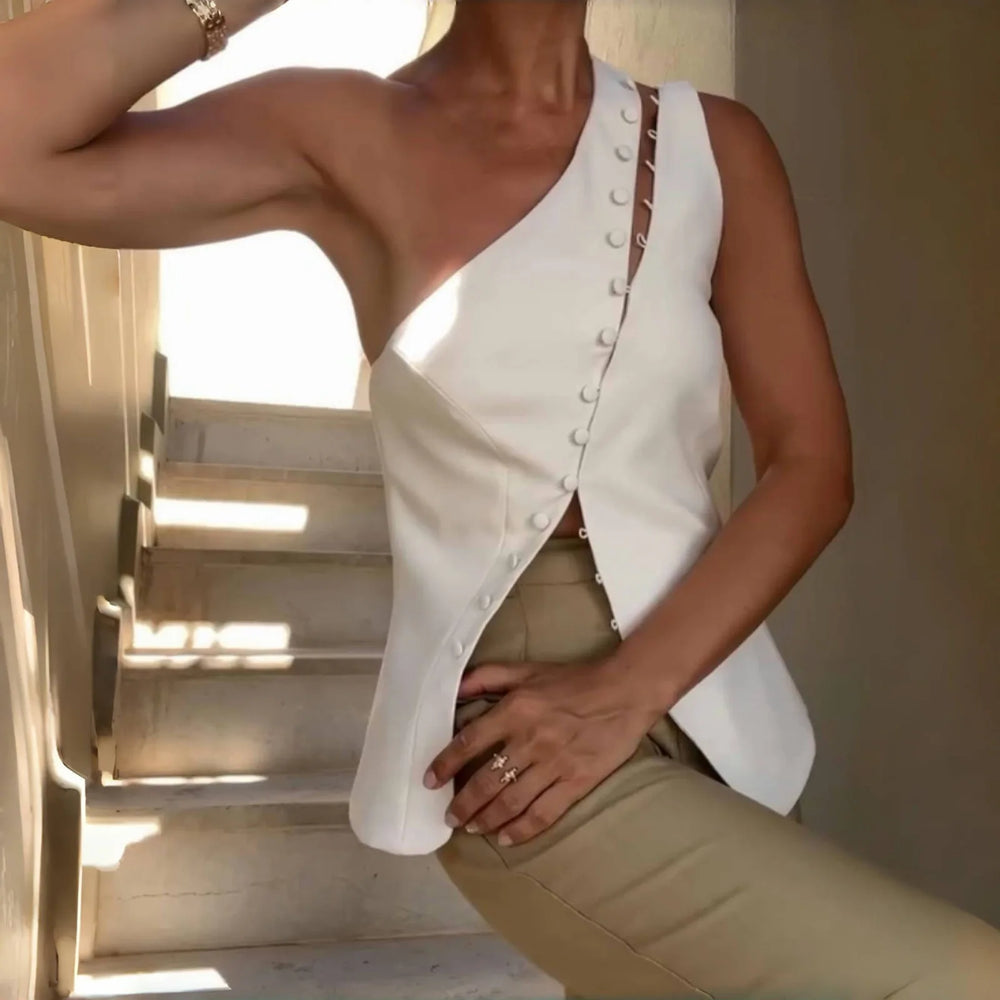Person wearing a white sleeveless top with buttons and beige pants on a staircase.