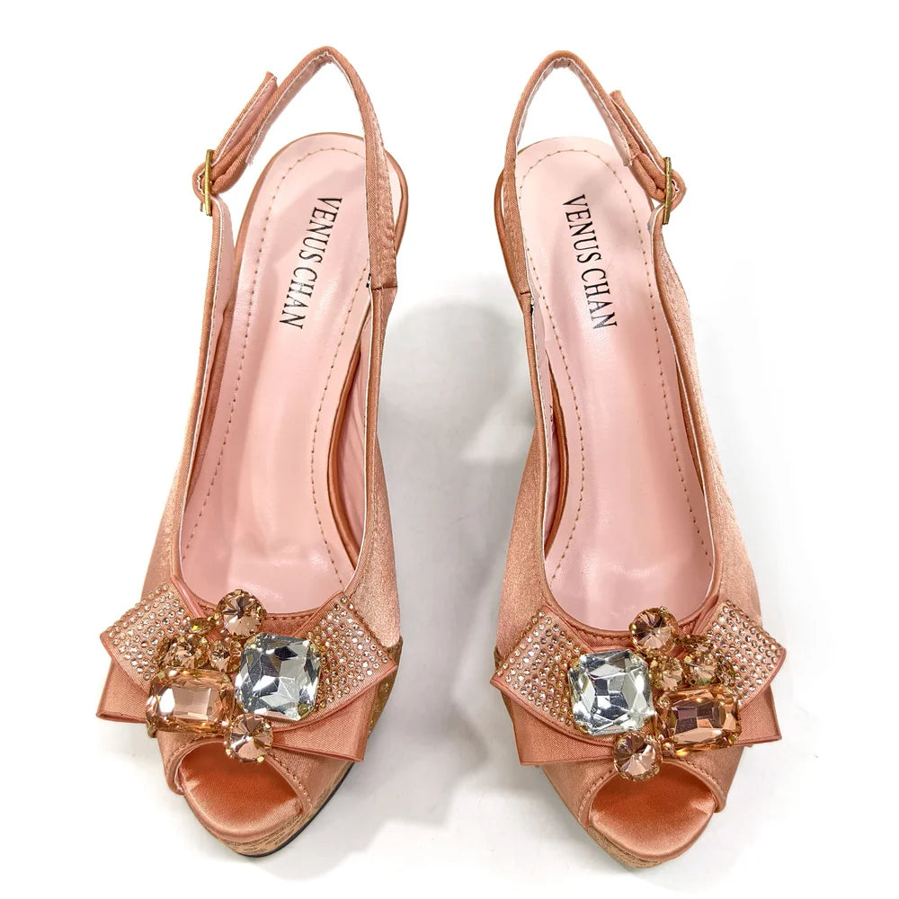 Pair of rose gold high-heeled shoes with embellishments on a white background