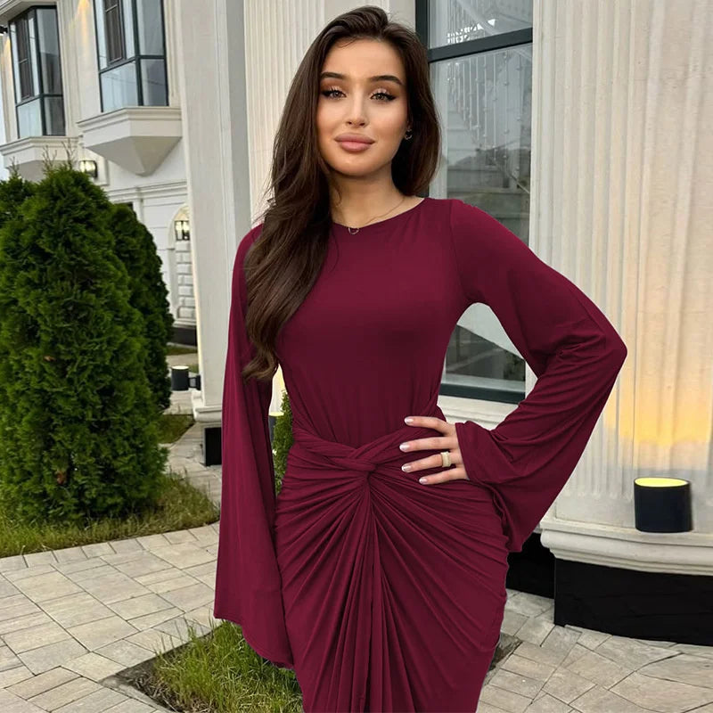 Woman in a burgundy dress standing outdoors in front of a building.