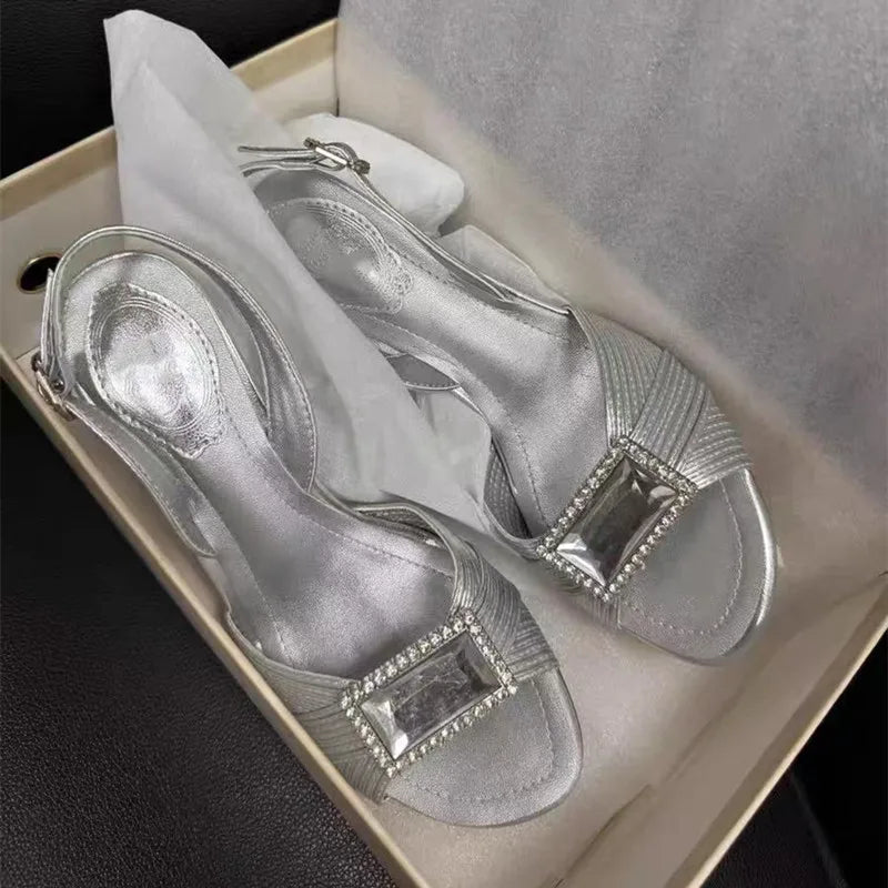 Silver high-heeled shoes with embellishments in a box