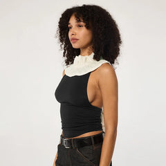 Woman wearing a black sleeveless top with a white collar against a plain background