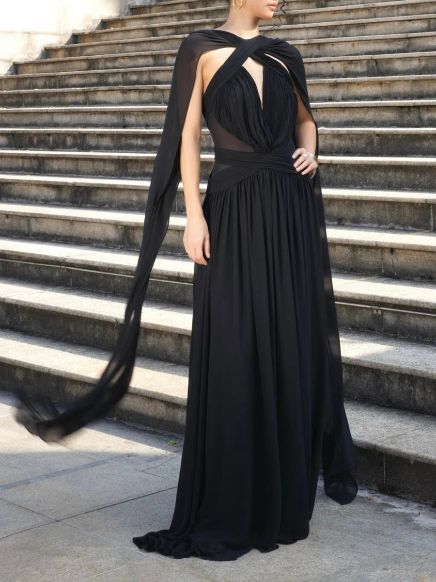 Person wearing a black evening gown with a cape on stone steps.