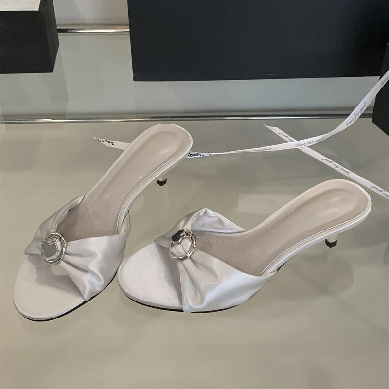 White high-heeled shoes with bow details on a reflective surface