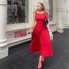 Woman in a red dress standing on a city street with storefronts in the background