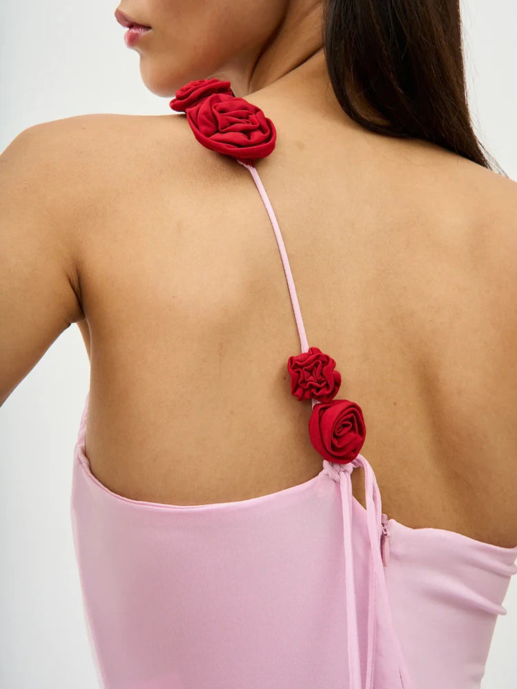 Pink dress with red floral straps on a plain background