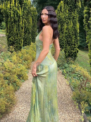 Woman in a green dress standing on a gravel path with greenery around