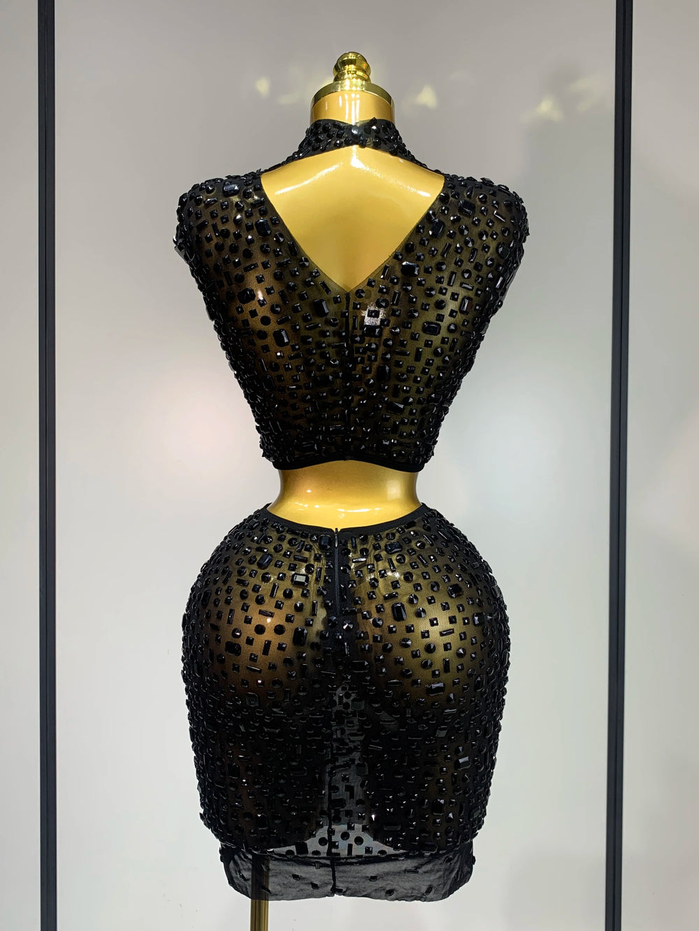 Black beaded dress on a mannequin against a neutral background