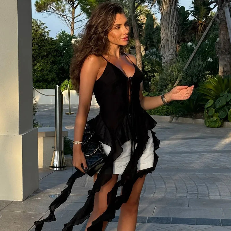 Woman in a black and white dress walking outdoors with greenery in the background