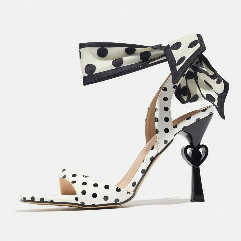 Polka dot high-heeled shoes with ribbon detail on a white background