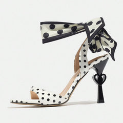 Polka dot high-heeled shoes with ribbon detail on a white background