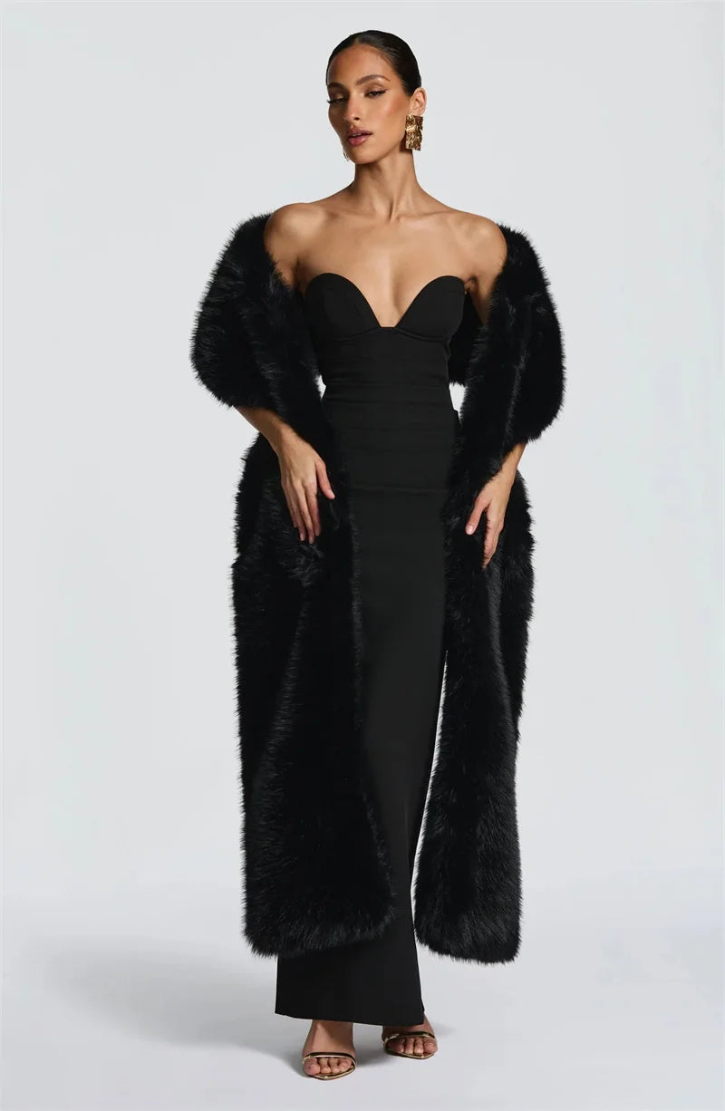 Woman wearing a black strapless dress with a fur coat on a white background